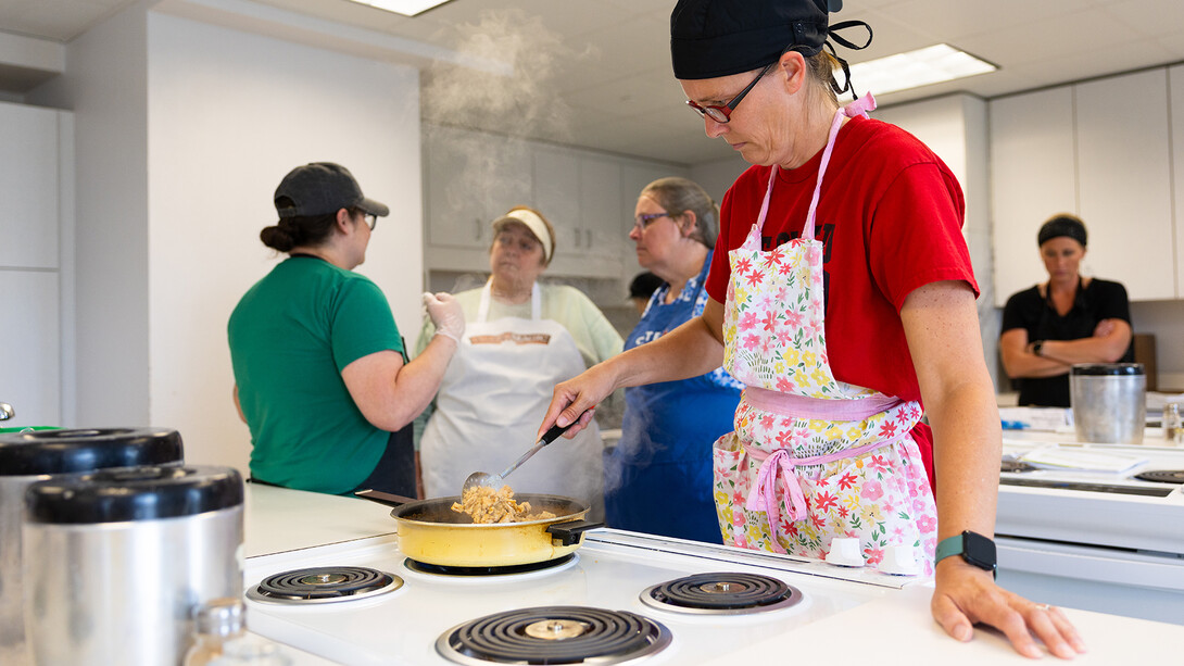 Lynsey Graham, director of nutrition services for Johnson County Central Public Schools, stirs a steaming pan of pulled chicken during a cooking class in Leverton Hall on June 4 as part of the Child Nutrition Training Academy. Graham is receiving her year two certification through the academy and is in her second year as a school nutrition professional after working 15 years in adult nutrition at long-term care facilities.